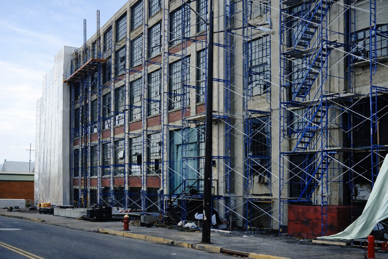 Industrial windows during restoration with scaffolding and active repair work in progress.